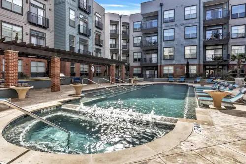 a pool with a fountain in front of a building at Modern 1BR CozySuites with pool, gym, parking #02 in Dallas