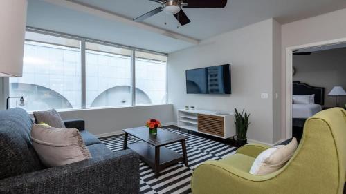 a living room with a couch and chairs and a tv at Bold CozySuites with gym, roof #7 in Dallas
