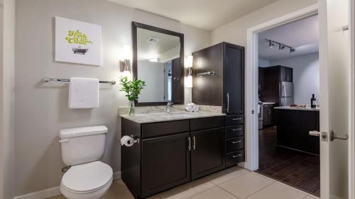 bagno con servizi igienici e lavandino con specchio di Bold CozySuites with pool, gym, roof #10 a Dallas