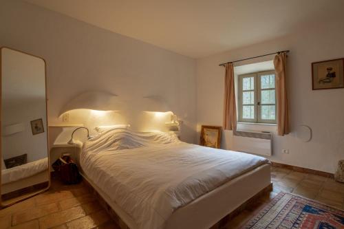 梅納的住宿－Campagne du Treyas，卧室配有一张白色大床和镜子