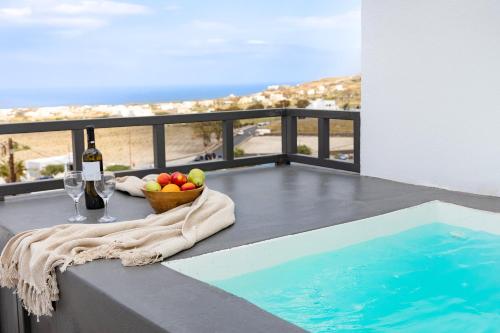 una mesa con un bol de frutas y copas de vino en el balcón en WHITE BREEZE VILLAS en Éxo Goniá