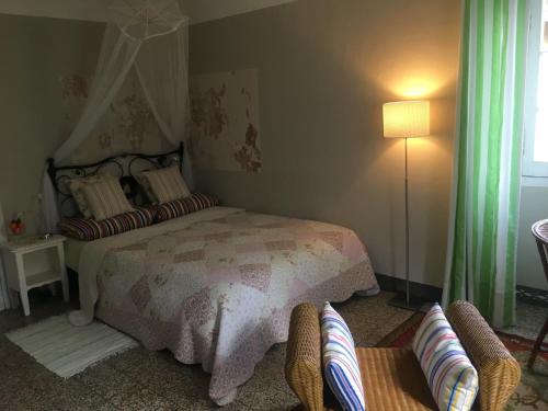 a bedroom with a bed and a chair and a lamp at Casa Rosalie in Borgomaro