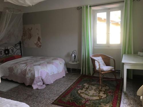 a bedroom with a bed and a chair and a window at Casa Rosalie in Borgomaro