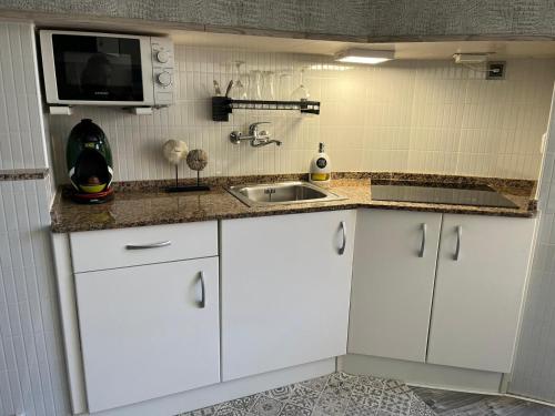 a white kitchen with a sink and a microwave at La Pineda playa in La Pineda
