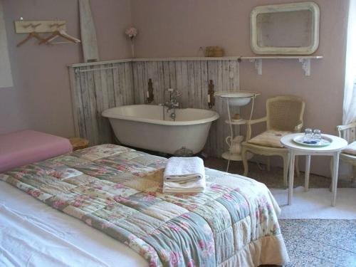 a bedroom with a tub and a bed and a sink at Casa Rosalie in Borgomaro