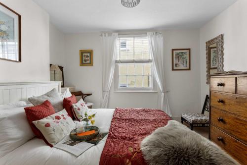 a bedroom with a white bed with red pillows and a window at The Admiralty Wash House in Dartmouth