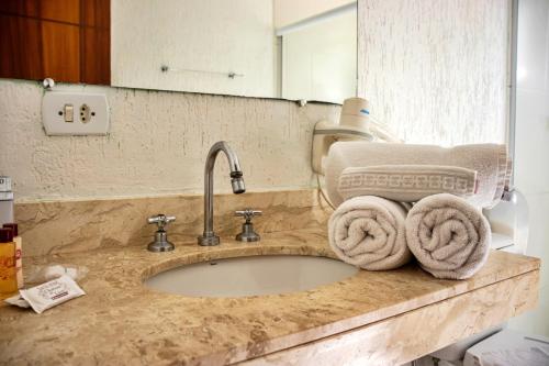 um balcão de casa de banho com um lavatório com toalhas em Chateau do Luar Prime em Campos do Jordao em Campos do Jordão