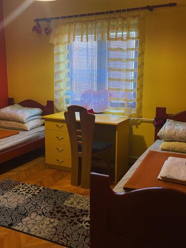 een slaapkamer met een bureau, een tafel en een raam bij Countryside Guest House in Nikšić