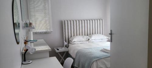 a small white bedroom with a bed and a desk at Innes Road Durban Accommodation 2 Bedroom Private Unit A in Durban