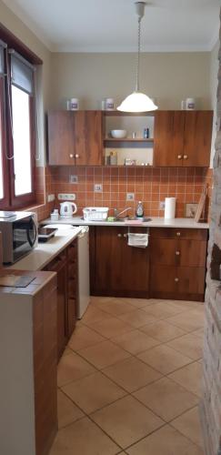 cocina con armarios de madera y suelo de baldosa en Protea Apartment, en Hódmezővásárhely