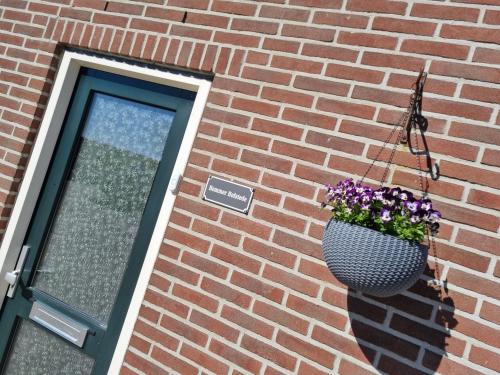 una maceta de flores colgando en un lado de un edificio de ladrillo en Hemmer Hofstede, en Hem