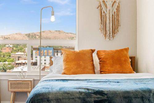 łóżko z pomarańczowymi poduszkami w pokoju z oknem w obiekcie City View - Downtown Walking Palace w mieście Salt Lake City