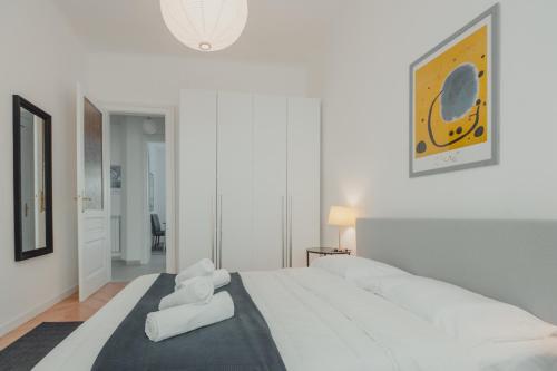una camera bianca con un grande letto con asciugamani di Piccardi a Trieste
