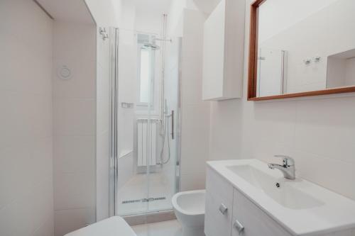 een witte badkamer met een douche en een wastafel bij Piccardi in Trieste
