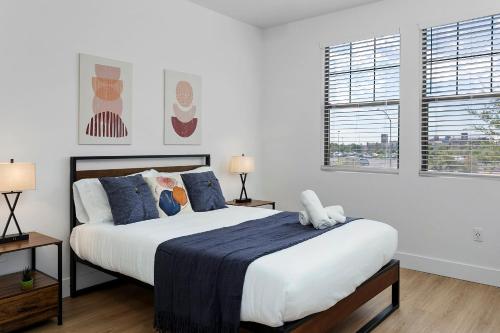 um quarto branco com uma cama grande e almofadas azuis em CozySuites Glendale by the stadium with pool 10 em Glendale