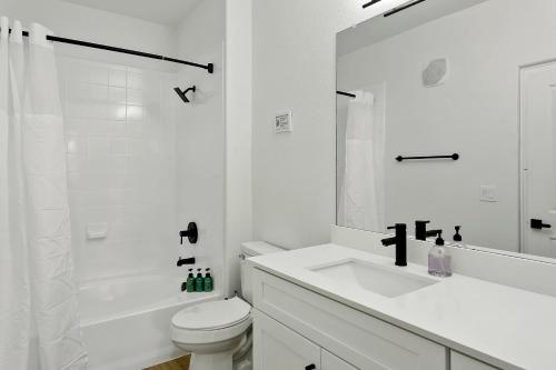 Baño blanco con lavabo y aseo en CozySuites Glendale by the stadium with pool 10 en Glendale