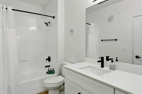 a white bathroom with a sink and a toilet at CozySuites Glendale by the stadium with pool 10 in Glendale