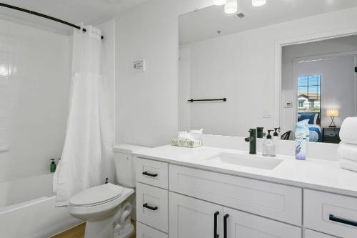 a white bathroom with a toilet and a sink at CozySuites Glendale by the stadium with pool 03 in Glendale