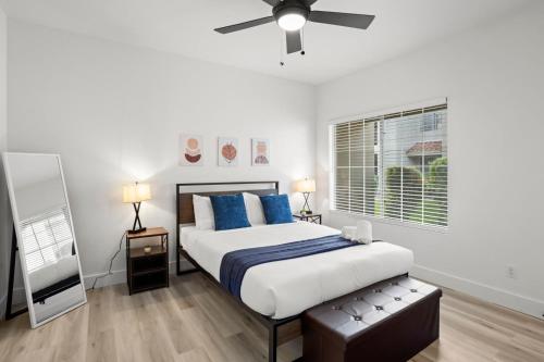 een slaapkamer met een bed met blauwe kussens en een plafondventilator bij CozySuites at TPC Scottsdale with parking and pool in Scottsdale