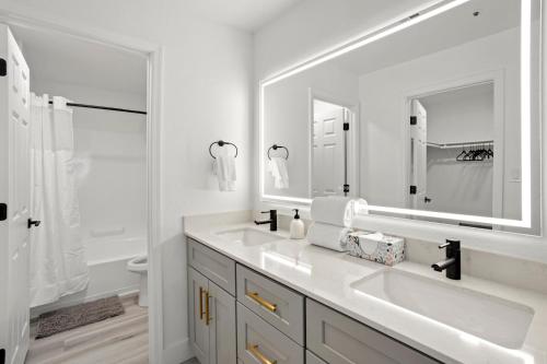 a white bathroom with two sinks and a large mirror at CozySuites at TPC Scottsdale with parking and pool in Scottsdale