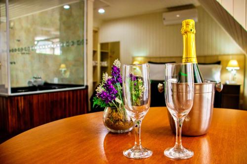 a table with three wine glasses and a bottle on it at Chateau do Luar Prime em Campos do Jordao in Campos do Jordão