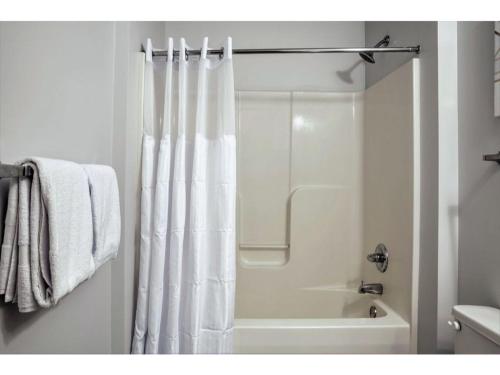 a bathroom with a shower with a white shower curtain at 2BR 2BA In The Block by CozySuites! in Indianapolis