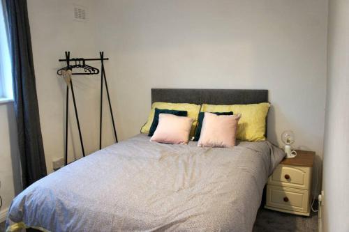 ein Schlafzimmer mit einem Bett mit zwei rosa Kissen in der Unterkunft Middleton, Manchester in Middleton