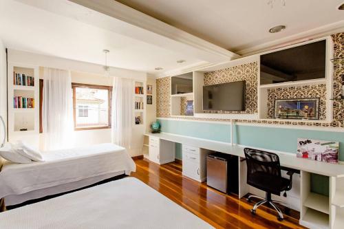 1 dormitorio con 1 cama, escritorio y TV en Pousada Dona Clô en Río de Janeiro