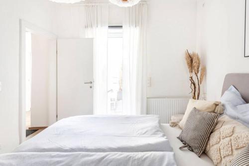 a white bedroom with a bed and a window at TheMarketFlat- Schöne Wohnung im Stadtzentrum in Klagenfurt