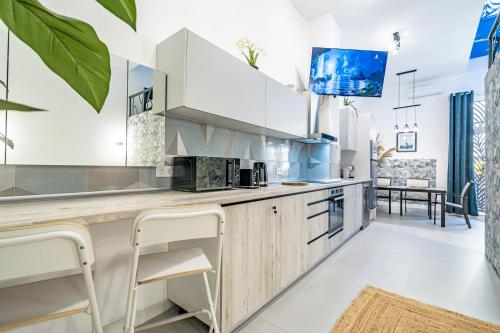 a kitchen with white cabinets and a counter with stools at Exquisite studio apartment with an original design in Valencia