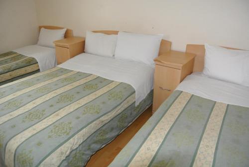 two beds in a room with white walls at The Belgrove Hotel in London
