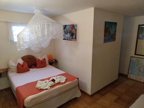 Schlafzimmer mit einem Bett mit weißer Bettwäsche und roten Kissen in der Unterkunft Gîte Morne Vent in Bois Neuf