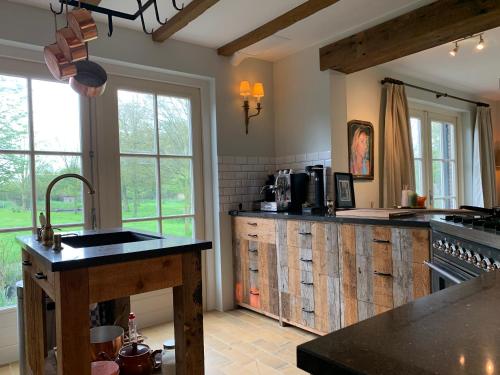 a large kitchen with wooden cabinets and a sink at Lovely warm Country home in Breukeleveen