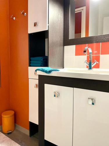 La salle de bains est pourvue d'un lavabo et d'un mur orange. dans l'établissement BUBBLE GOM'Z, à Saint-Hilaire-de-Riez