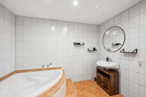 een badkamer met een bad, een wastafel en een spiegel bij Sali Homes - Auszeit am Fuß der Burg Stettenfels in Untergruppenbach