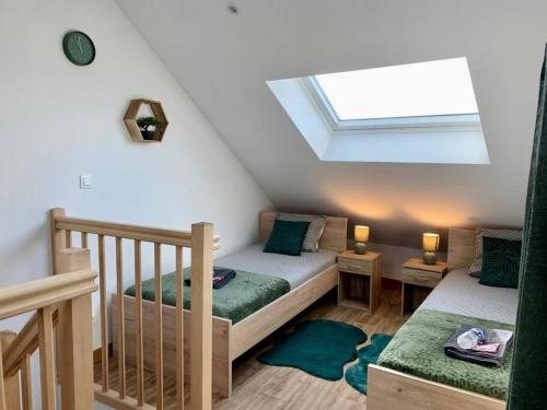 une chambre mansardée avec deux lits et une lucarne dans l'établissement Maison 3 chambres - 600m Métro Marbrerie - Lille, à Mons-en-Baroeul