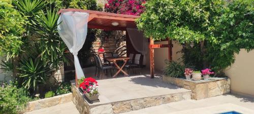 a patio with a gazebo and a table with flowers at Villa Anthemida Chania in Ayiá