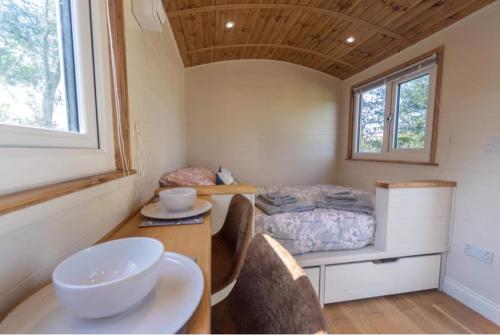 Habitación pequeña con cama, escritorio y mesa. en Berllan Y Bugail Shepherds Hut, en Llanwrda