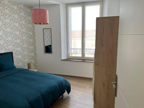 a bedroom with a blue bed and a window at Le 202 de la gare: appartement neuf et climatisé in Chalons en Champagne