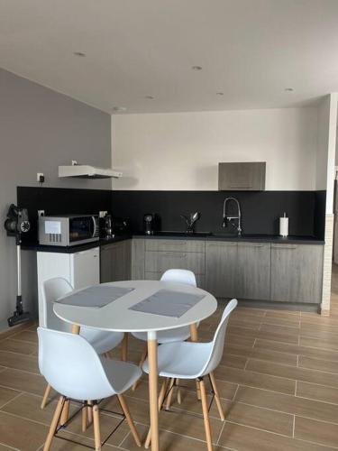 une cuisine avec une table et des chaises dans une pièce dans l'établissement Le 202 de la gare: appartement neuf et climatisé, à Châlons-en-Champagne