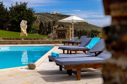 a pool with two lounge chairs and an umbrella at Marble Villas in Tinos Town