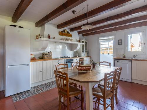 une cuisine avec une table en bois et un réfrigérateur blanc dans l'établissement Maison landaise 3* à Mimizan, 7 pers, WiFi, clim, proche océan - FR-1-50-103, à Mimizan