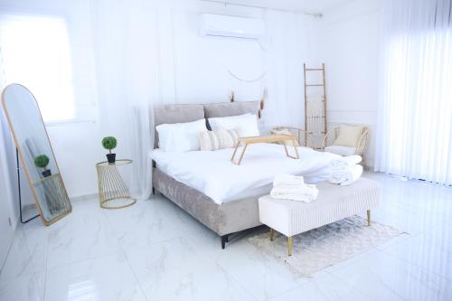 Dormitorio blanco con cama, mesa y espejo en סוויטות נוף שקיעה, en Peqi‘in H̱adasha