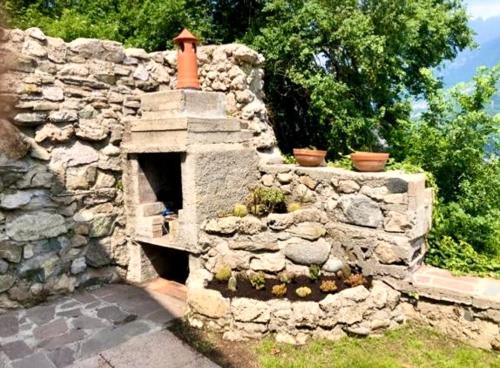 a stone wall with an outdoor oven in a yard at La Dimora Degli Olivi Dependance in Galbiate