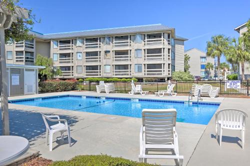 a swimming pool with white chairs and a building at Pool Access and Views at Saint Helena Island Condo! in Oceanmarsh Subdivision