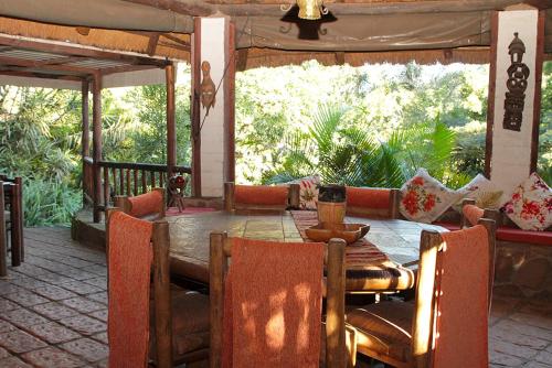 uma sala de jantar com uma mesa de madeira e cadeiras em Treehouse River Lodge em Elangeni