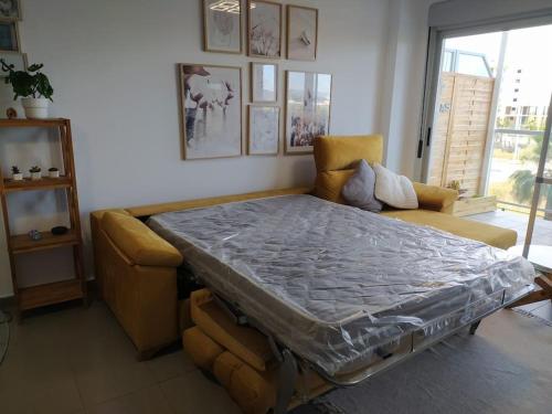 a bed in a room with a couch and a window at Lovely 1bed apartment with padel court near beach in Moncófar