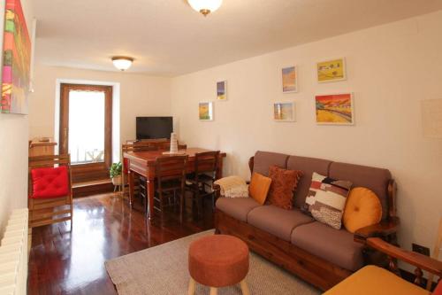 uma sala de estar com um sofá e uma mesa em Maison Baradis - grazioso e tranquillo trilocale con vista montagne em Allein