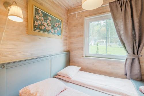 a small bedroom with a window and a bed at Domki w Dolinie Wieżycy in Szymbark