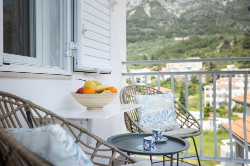 - une table et des chaises sur un balcon avec un bol de fruits dans l'établissement Apartments Nikolic, à Gradac